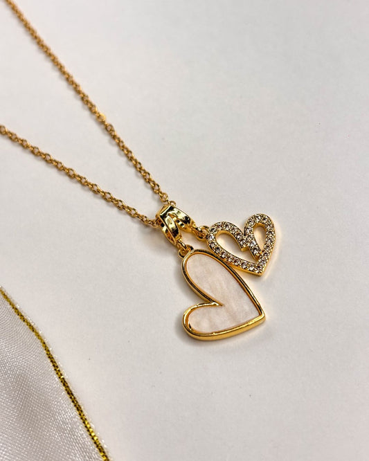 Gold necklace with heart-shaped pendants on a light background